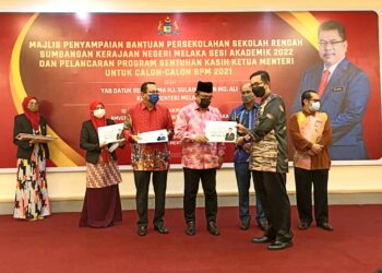 SULAIMAN Md. Ali (tiga dari kanan) menyampaikan bantuan sekolah rendah daripada Tapem kepada salah seorang guru besar di Amverton Heritage Resort, Ayer Keroh, Melaka. - UTUSAN/AMRAN MULUP