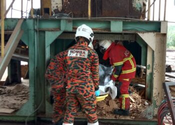 ANGGOTA bomba mengeluarkan mayat mangsa yang terjatuh ke dalam mesin pengisar kayu dalam kejadian di sebuah kilang di Kawasan Perindustrian Nilai, Nilai, Seremban pagi tadi. - GAMBAR IHSAN BOMBA