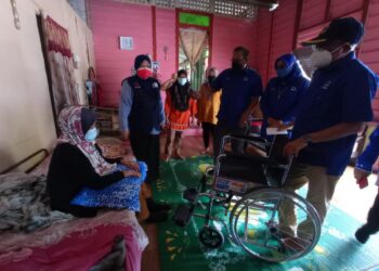 MOHD. Youzaimi Yusof (kanan) menyerahkan kerusi roda kepada salah seorang penduduk yang dilawati pada program ziarah kasih di Kampung Penyabong, Mersing di Johor. -UTUSAN/MASTURAH SURADI
