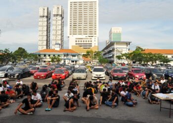 ANTARA individu yang ditahan termasuk deretan kereta di bahagian belakang dalam Operasi Samseng Jalanan membabitkan kegiatan lumba haram di IPK Johor di Johor Bahru. -UTUSAN/RAJA JAAFAR ALI