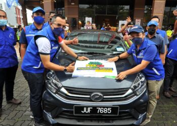 ASYRAF Wajdi Dusuki (kiri) bersama Noor Azleen Ambros (kanan) menampal pelekat Pickids sempena Program Pengangkutan Percuma Pickids di Pejabat UMNO Bahagian Pasir Gudang, Bandar Seri Alam, Pasir Gudang. - UTUSAN/RAJA JAAFAR ALI