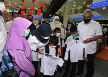 NOH Omar (kanan) membantu beberapa murid mencuba uniform baharu pada Majlis Back To School di Angsana Mall, Johor Bahru. -UTUSAN/RAJA JAAFAR ALI