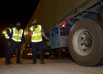MOHAMMAD Yusoff Abustan (kanan) memeriksa tayar sebuah lori ketika Operasi Bersepadu Kenderaan Perdagangan di Plaza Tol Ipoh Utara (Arah Selatan) semalam. - UTUSAN/ZULFACHRI ZULKIFLI