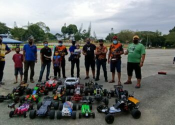 NORDIN Jasni (lima dari kanan) sedang memangku anaknya, Mohd. Aqil Aqmar menyaksikan deretan kereta lumba kawalan jarak jauh bersama ahli Kelab RC Temerloh di Dataran Temerloh di Temerloh, Pahang. - FOTO/HARIS FADILAH AHMAD