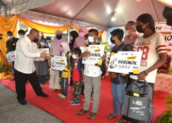 SAARANI Mohamad (kiri) beramah mesra dengan murid yang menerima kelengkapan persekolahan pada Program Seronok Ke Sekolah di Ipoh hari ini. - UTUSAN/ZULFACHRI ZULKIFLI