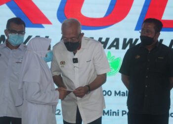 MAHDZIR Khalid (tengah) menyampaikan bantuan wang tunai daripada Yayasan Pelajaran Mara (YPM) kepada pelajar sempena Mini KUD di Stadium Mini Pontian, Johor.