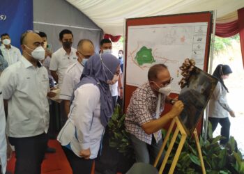 WAN ROSDY Wan Ismail (tunduk, kanan) diiringi Roslina Yusop (kiri) menandatangani plak selepas merasmikan projek pembinaan Off River Storage (ORS) atau Kolam Takungan Hiliran di Kuala Medang di Lipis, Pahang. - FOTO/HARIS FADILAH AHMAD