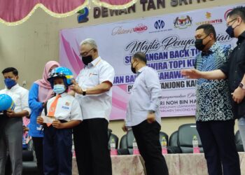 NOH Omar menyerahkan topi keledar kepada murid dan guru besar sekolah Parlimen Tanjong Karang pada program itu dekat IPP Tanjong Karang di Kuala Selangor, Selangor hari ini.