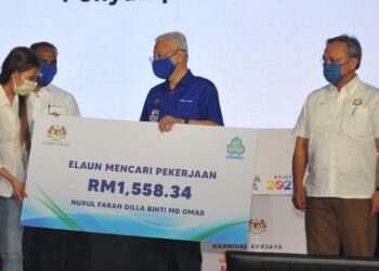 ISMAIL Sabri Yaakob menyampaikan replika cek kepada salah seorang pekerja yang mendapat faedah skim insurans pekerjaan sempena Karnival Kerjaya Jamin Kerja Keluarga Malaysia 2022 Johor sambil diperhatikan Hasni Mohammad dan M. Saravanan di Dewan Jubli Intan Sultan Ibrahim, Pontian. - UTUSAN/RAJA JAAFAR ALI