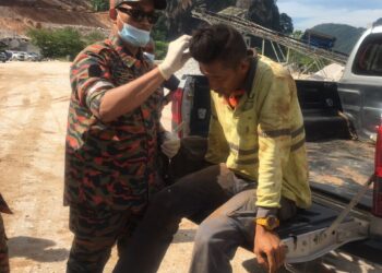 SEORANG mangsa diberikan rawatan awal oleh anggota bomba selepas terlibat dalam kejadian runtuhan batu kuari di Keramai Pulai, Simpang Pulai di Ipoh hari ini. - UTUSAN/IHSAN JBPM PERAK