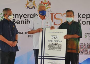 ISMAIL Sabri Yaakob menyampaikan replika benih padi IS21 kepada wakil komuniti sempena majlis penyerahan di Felcra Seri Mahkota, Endau, Mersing. -UTUSAN/ RAJA JAAFAR ALI