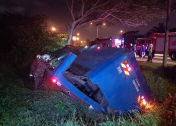 ANGGOTA bomba memeriksa keadaan bas yang terbalik dalam kejadian di Jalan Bukit Mutiara, Bandar Dato Onn, Johor Bahru, semalam.