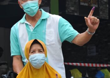 SEPASANG suami isteri warga emas, Rashid Idros bersama isterinya, Fauziah yang berkerusi roda menunaikan tanggungjawap dengan mengundi pada PRN Johor di SMK Permas Jaya, Bandar Baru Permas Jaya. - UTUSAN/RAJA JAAFAR ALI