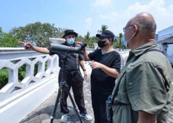 MUHAMMAD Jailani Khamis (tengah) tidak ketinggalan untuk melihat kehadiran burung pemangsa di Rumah Api Tanjung Tuan hari ini. - UTUSAN/MOHD. SHAHJEHAN MAAMIN
