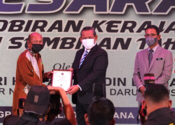 AMINUDDIN Harun (tengah) menyampaikan sijil penghargaan kepada salah seorang penerima pada Majlis Penghargaan Pesara Pentadbiran Kerajaan Negeri Sembilan Tahun 2021 di Seremban hari ini. - UTUSAN/BADRUL HAFIZAN MAT ISA