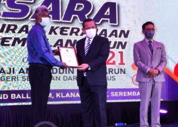 AMINUDDIN Harun (tengah) menyampaikan sijil penghargaan kepada salah seorang penerima pada Majlis Penghargaan Pesara Pentadbiran Kerajaan Negeri Sembilan Tahun 2021 di Seremban hari ini. - UTUSAN/BADRUL HAFIZAN MAT ISA
