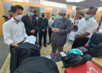 MOHAMED Fadzli Hassan (dua dari kanan) melihat kelengkapan seragam sekolah yang diserahkan secara simbolik oleh Yayasan Petronas untuk diagihkan kepada 4,200 penerima di Kelantan.