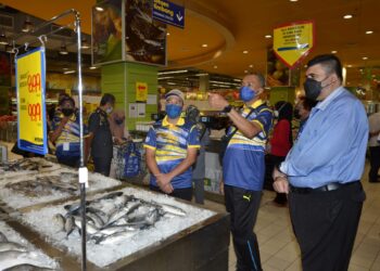 ABDUL Yunus Jamahri (tiga dari kanan) meninjau harga barang pada Program Jualan Keluarga Malaysia di Ipoh hari ini. - UTUSAN/ZULFACHRI ZULKIFLI