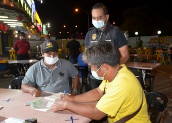 ANGGOTA penguat kuasaan kesihatan (kiri) mengeluarkan kompaun kepada individu yang melakukan kesalahan merokok di tempat awam dalam operasi di sekitar bandaraya Ipoh semalam. - UTUSAN/ZULFACHRI ZULKIFLI
