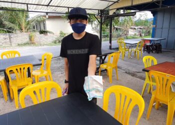 SEORANG pekerja kedai makan menunjukkan debu yang melekat di meja ketika tinjauan di Dungun, hari ini. - UTUSAN/NIK NUR IZZATUL HAZWANI NIK ADNAN