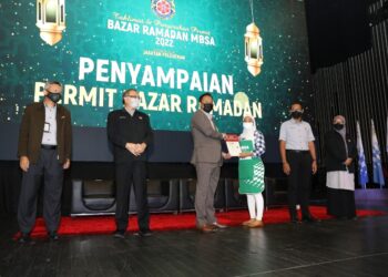MOHD. Rashidi Ruslan (tengah) menyampaikan permit kepada seorang peserta Bazar Ramadan MBSA di Shah Alam, Selangor, hari ini. - UTUSAN / ABDUL RAZAK IDRIS