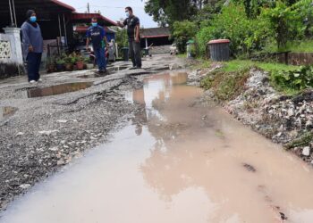 ROSMAN Hayazi (kanan) menunjukkan keadaan jalan yang rosak teruk di Taman Kenangan, Sungai Karangan, Kulim. - UTUSAN/AZAHAR HASHIM
