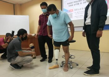 KAKITANGAN UTM memakaikan kaki palsu yang dihasilkan dengan kerjasama 3D Gens kepada penerima, Muhammad Sabri Ramli di Fakulti Kejuruteraan UTM Kampus Johor Bahru, di sini.