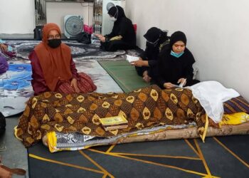 YUSRIATI Mohd. Yunos (kanan) membacakan surah Yasin di sisi jenazah Allahyarham Mohd. Azizan Baba di Kampung Bakar Batu, Bachang, Melaka. - UTUSAN/AMRAN MULUP
