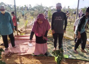 NUR Suriati Yusoff menyiram kubur anaknya selepas pengebumian di Tanah Perkuburan Islam Masjid At Taqwa, Kubu Gajah Gunung Semanggol dekat Bagan Serai hari ini. - UTUSAN/WAT KAMAL ABAS