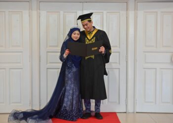 NUR Izzatul Nabilah Ghazali menemani Ameerul Hakim Muzi@Ahmad Fauzi menerima ijazah selepas empat jam mereka bernikah di Universiti Sultan Zainal Abidin (Unisza) di Kuala Nerus, hari ini. - UTUSAN/PUQTRA HAIRRY ROSLI