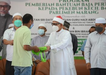 ABDUL Hadi Awang (tengah) di samping Azman Ibrahim (kanan) menyampaikan bantuan kepada pekebun di Dewan Tok Guru, Rusila di Marang hari ini. - UTUSAN/PUQTRA HAIRRY ROSLI