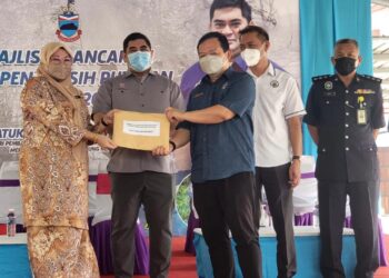 SHAHELMEY Yahya (dua kiri) menyaksikan penyerahan borang pertandingan kebersihan kampung di Putatan hari ini.