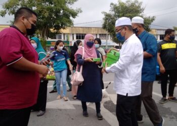 NOOR Azmi Ghazali (kanan) menyampaikan sumbangan buah kurma kepada pengunjung bazar Ramadan di Jalan Raja Syed Thauphy di Bagan Serai semalam. - UTUSAN/WAT KAMAL ABAS