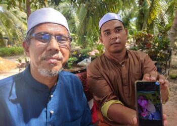 MUHAMMAD Farid Arbak (kanan) dan bapanya, Arbak Atan menunjukkan gambar Allahyarham yang maut kemalangan di Jalan Sungai Terap, Kampung Sungai Yu di Kuala Selangor, Selangor, semalam.