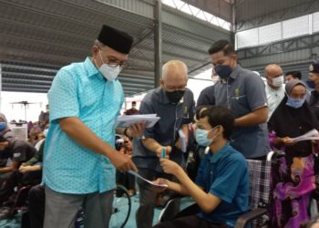 WAN ROSDY Wan Ismail (kiri) menyampaikan sumbangan Iftar Ramadan kepada Amar Hakim Jamil di Laman Sejahtera Sungai Koyan di Lipis, Pahang. - UTUSAN/HARIS FADILAH AHMAD