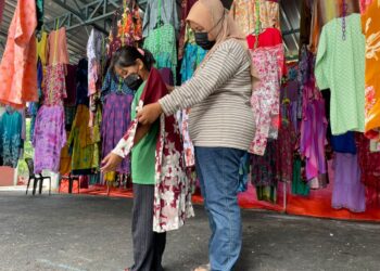 ROZITA Samad mengukur saiz baju kurung pada anaknya, Nur Zahra Farhana Othman, 9, di Butik Rakyat 3.0 Keluarga Malaysia di RUTC Klebang Besar, Melaka. - UTUSAN/DIYANATUL ATIQAH ZAKARYA