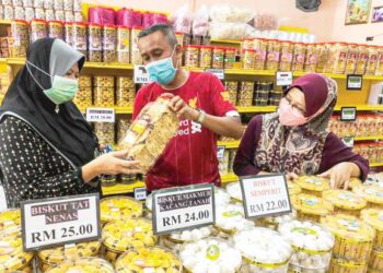 SAIFUL Bahari Ikhwan melayan pelanggan yang berkunjung ke premis jualan mereka untuk mendapatkan rempeyek sempena Hari Raya Aidilfitri di Kampung Tengah, Kluang, Johor. – UTUSAN/NUR NABILAH RAHMAT