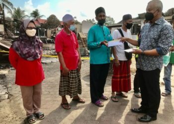 ABDUL Halim Shafai (kanan) menyampaikan bantuan wang hasil derma kilat kepada mangsa kebakaran di Kampung Dalam Rhu, Tumpat semalam. – UTUSAN/ROSLIZA MOHAMED