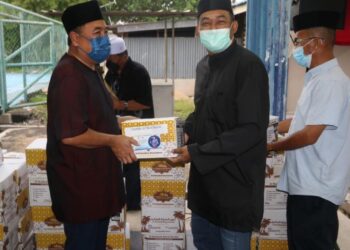 ISMAIL Mohamed Said (kiri) menyampaikan kurma kepada pengerusi kawasan rukun tetangga (KRT) di Wisma Peneroka Bandar Abdul Razak Jengka di Kuala Krau, Pahang. - UTUSAN/SALEHUDIN MAT RASAD