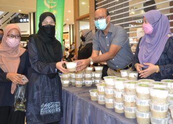 AZMAN Mohd. Yusof (dua dari kanan) mengedarkan bubur lambuk kepada pengunjung sempena Program Bubur Lambuk AEON Bersama Komuniti Bersempena Bulan Ramadan di Nilai, Seremban hari ini.- UTUSAN/ZAKKINA WATI AHMAD TARMIZI