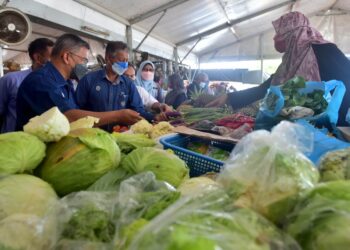 AZMAN Ibrahim (kiri) memeriksa bekalan terung yang dijual di Pasar Payang di Kuala Terengganu, hari ini.