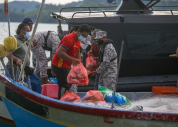 MOHD. Zawawi Abdullah menyampaikan sumbangan bungkusan keperluan makanan asas kepada komuniti maritim di perairan Langkawi, Langkawi semalam. - UTUSAN/SHAHIR NOORDIN