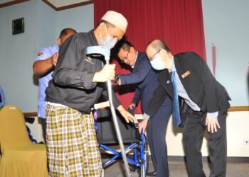 MOHD. Hairi Mad Shah (dua dari kanan) membantu Hasnul Hisham duduk di atas kerusi roda yang diterimanya sambil dibantu Tong Sing Chuang (kanan) sempena Program Solidariti Ramadan Prihatin @ Perkeso di bangunan Perkeso Johor, Johor Bahru. - UTUSAN/RAJA JAAFAR ALI