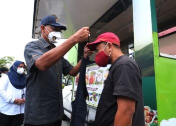 ROSOL Wahid menyarungkan apron kepada salah seorang pengusaha trak makanan ketika mengadakan walkabout Program Jualan Malaysia 'Rancak Aidilfitri' di Nilai, Seremban semalam-UTUSAN/BADRUL HAFIZAN MAT ISA.