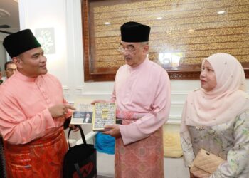AZIZAN Osman (kiri) menunjukkan buku tulisannya kepada Mohd. Ali Mohd. Rustam ketika bertemu pada majlis rumah terbuka Aidilfitri di Tengkera, Melaka. - UTUSAN/DIYANATUL ATIQAH ZAKARYA