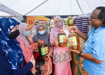Adnan Hanif bersama pembeli yang singgah di gerai jualan barangan murah di FGM 2022.