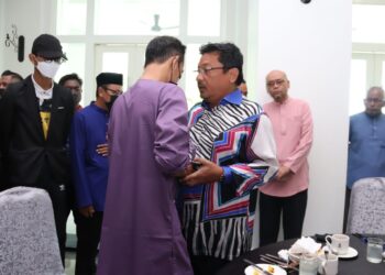 SYED Mohd. Fazmi Sayid Mohamad (kanan) menenangkan seorang ahli keluarga pelajar USAS ketika menyampaikan sumbangan Perdana Menteri kepada mereka di Kuala Kangsar hari ini. - UTUSAN/MUHAMAD NAZREEN SYAH MUSTHAFA