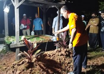 SEORANG ahli keluarga Ahmad Akmal Ahmad Mokhlis menyiram air mawar di atas kubur Allahyarham pada pengebumian di Masjid Hijau Kampung Kedah, Parit Buntar malam tadi. - UTUSAN/WAT KAMAL ABAS