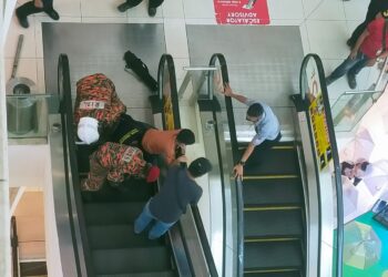 ANGGOTA bomba dibantu orang ramai mengeluarkan kaki kanak-kanak yang tersepit pada eskalator di sebuah pusat membeli-belah di Alor Setar. - UTUSAN/MOHD. RAFIE AZIMI