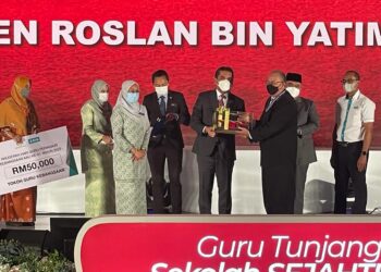 RADZI Jidin (tiga kiri) menyampaikan hadiah tajaan BSN kepada Tokoh Guru Kebangsaan 2022, Roslan Yatim pada sambutan Hari Guru Peringkat Kebangsaan Kali Ke-5 Tahun 2022 di UMK Kampus Bachok, hari ini. - UTUSAN/TOREK SULONG